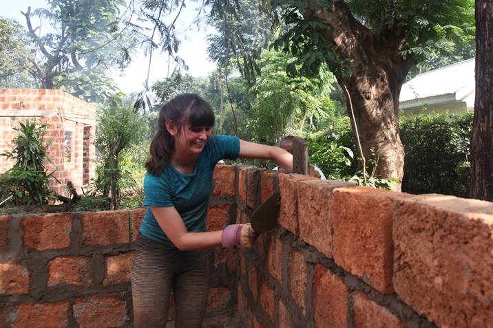 Woman building a wall, adding mortar