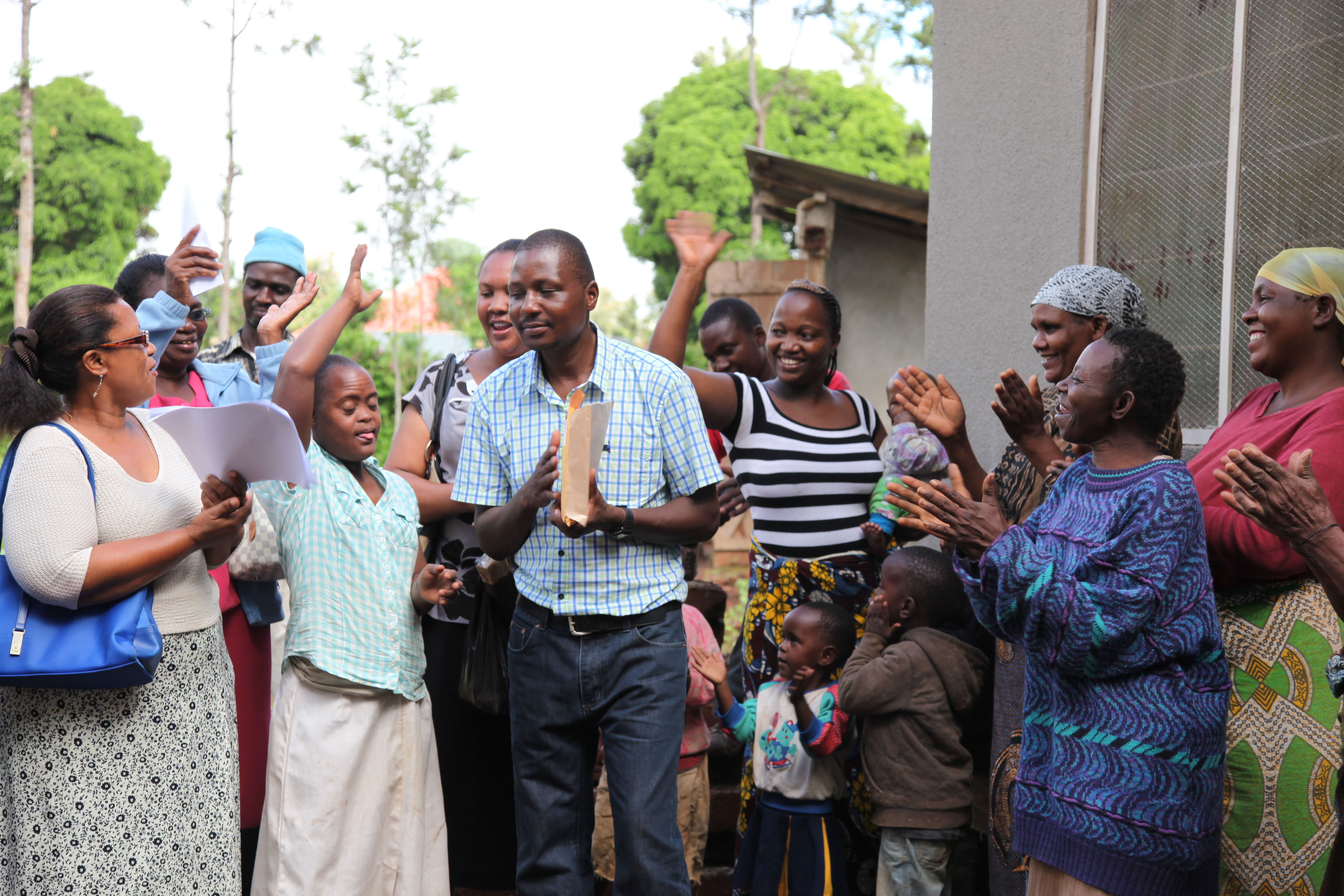 Community members outside a new house TAWREF